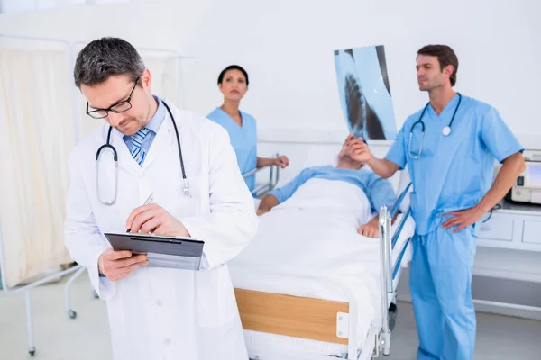 Doctors holding reports by patient at hospital — Stock Photo, Image