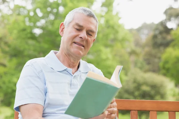 Äldre man läser en bok på park — Stockfoto