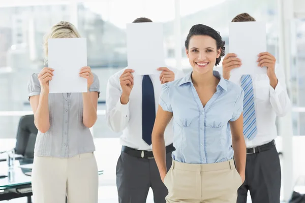 Empresaria con colegas sosteniendo papel en blanco delante de fa — Foto de Stock