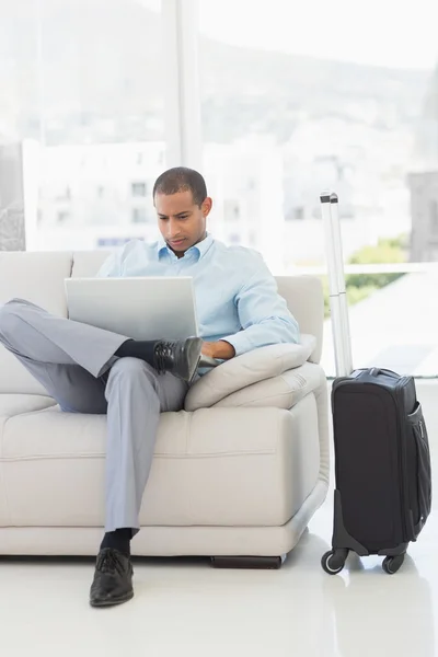 Uomo d'affari che utilizza computer portatile seduto sul divano in attesa di partire su bu — Foto Stock