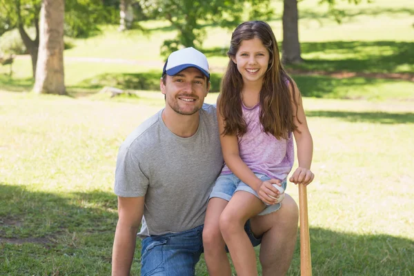 Father and daughter holding baseball bat in park — Stock Photo, Image