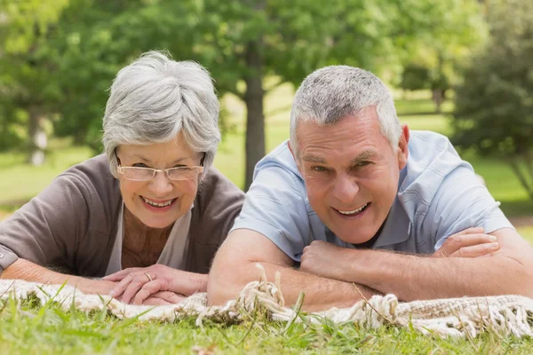 Portrait of senior couple lying at park — Stock Photo, Image