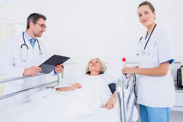 Médicos visitando a una paciente femenina en el hospital — Foto de Stock