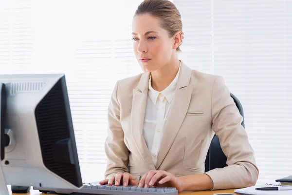Серьёзная деловая женщина с компьютером в офисе — стоковое фото