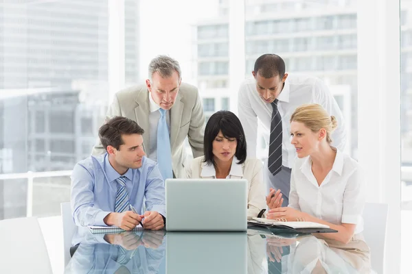 Business people gathered around laptop talking — Stock Photo, Image