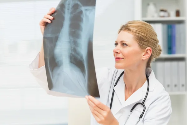 Doutor examinando um raio-x sentado em sua mesa — Fotografia de Stock