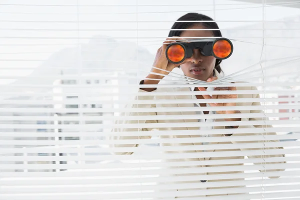 Businessman peeking with binoculars through blinds — Stock Photo, Image