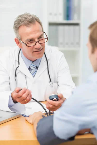 Lachende volwassen arts nemen van zijn patiënten bloeddruk — Stockfoto