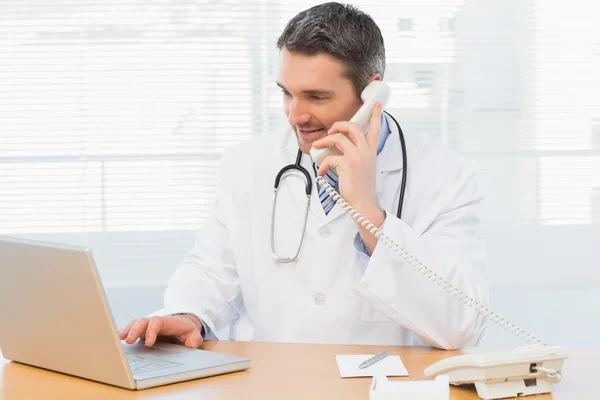 Концентрация врача с помощью ноутбука и телефона — стоковое фото