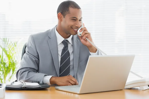 Zakenman met behulp van laptop en telefoon op Bureau — Stockfoto