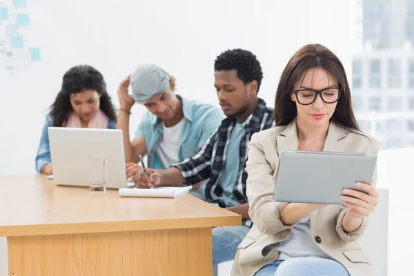 Mujer concentrada usando tableta digital con colegas detrás de i — Foto de Stock
