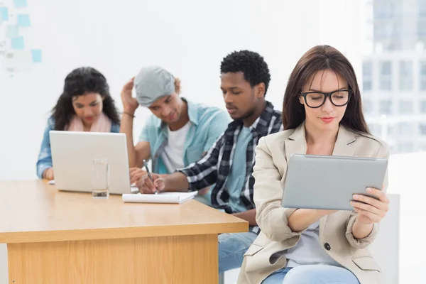 Vrouw met behulp van digitale tablet met collega's achter ik geconcentreerd — Stockfoto