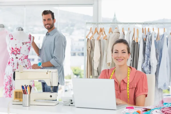 Femme utilisant un ordinateur portable avec créateur de mode travaillant au studio — Photo