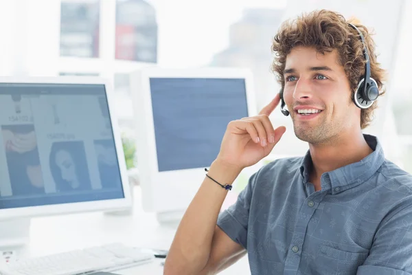 Glimlachend casual jonge man met hoofdtelefoon in office — Stockfoto