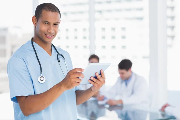 Murgeon using digital tablet with group around table in hospital — Stock Photo, Image