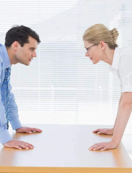 Business couple looking at each other with palms at desk — Stock Photo, Image