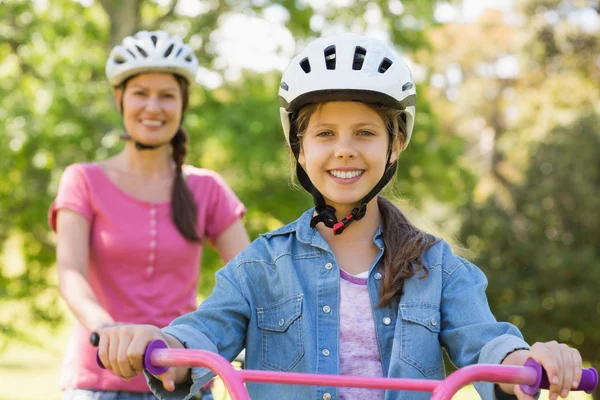 Mulher sorridente com sua filha andando de bicicleta — Fotografia de Stock