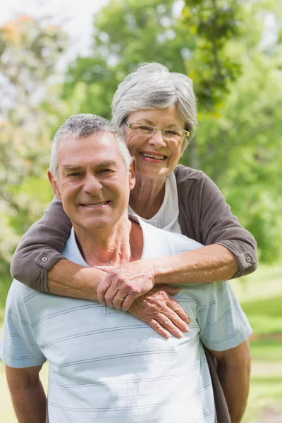 Senior woman embracing man from behind at park — Stock Photo, Image