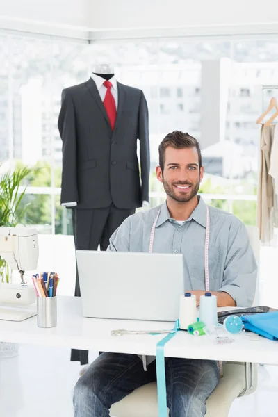 Sonriente diseñador de moda masculino usando el ordenador portátil en el estudio —  Fotos de Stock