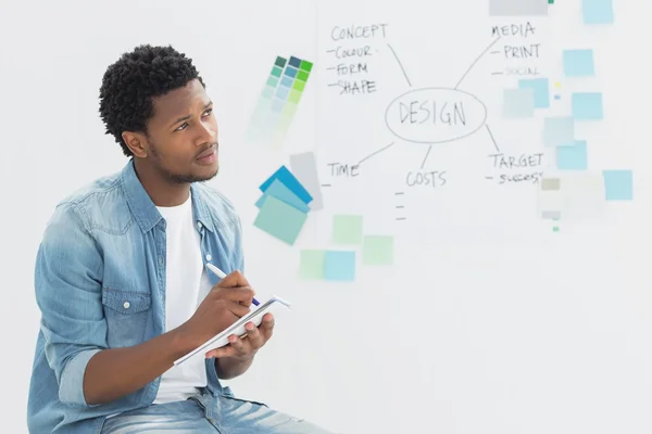 Thoughtful artist writing notes in front of whiteboard — Stock Photo, Image