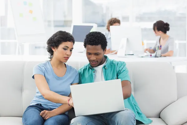 Pareja usando portátil con colegas en la oficina creativa — Foto de Stock