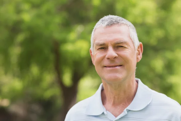 Portret van een glimlachende senior man in het park — Stockfoto