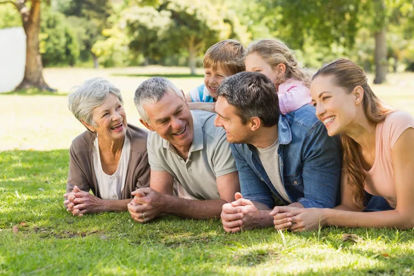 Uitgebreide familie liggen op gras in park — Stockfoto