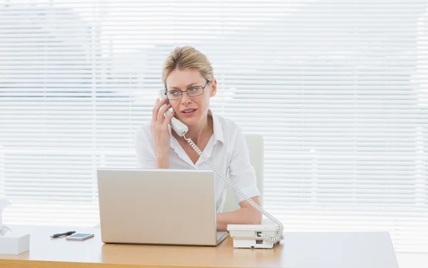 Kobieta za pomocą laptopa i telefon na biurko — Zdjęcie stockowe