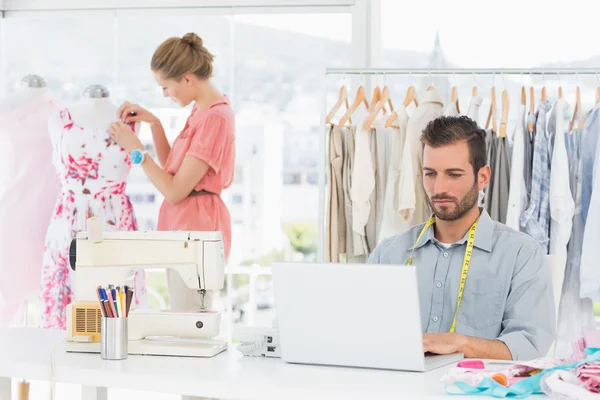 Hombre usando portátil con diseñador de moda trabajando en el estudio — Foto de Stock