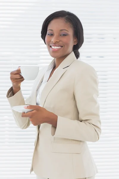 Elegante donna d'affari sorridente con tazza di tè in ufficio — Foto Stock