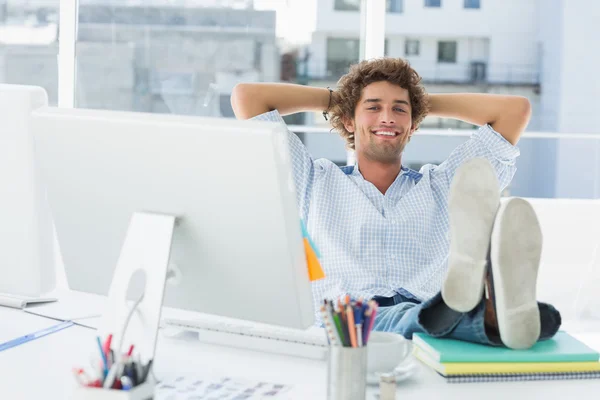 Avslappnad casual man med benen på skrivbord i ljust kontor — Stockfoto