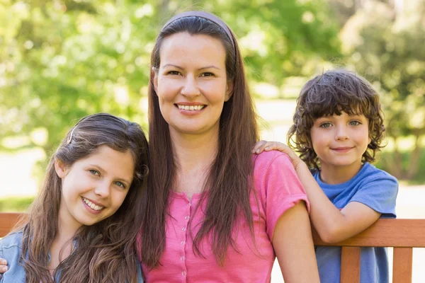 Lachende vrouw met kinderen zittend op een bankje — Stockfoto