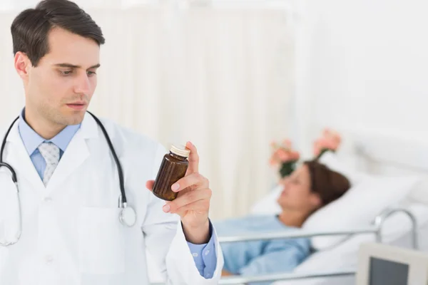 Doctor holding a bottle of pills with patient in hospital — Stock Photo, Image