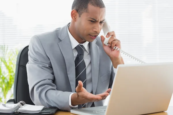 Geconcentreerde zakenman met behulp laptop en telefoon — Stockfoto