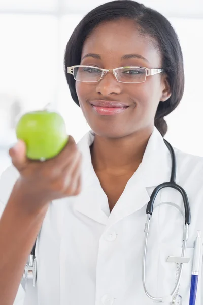 リンゴを保持笑みを浮かべて女性医師の肖像画 — ストック写真