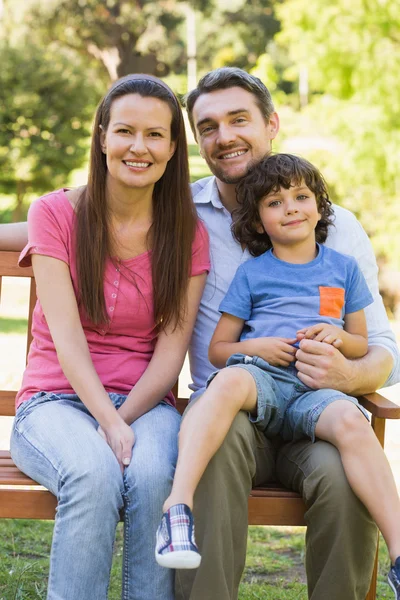 Sorrindo casal com filho sentado no banco do parque — Fotografia de Stock