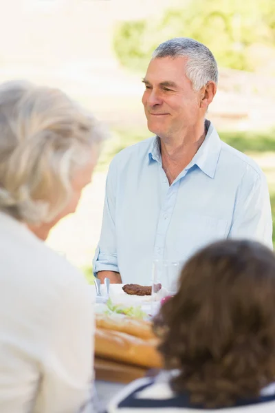 Äldre man med familj på utomhus matbord — Stockfoto