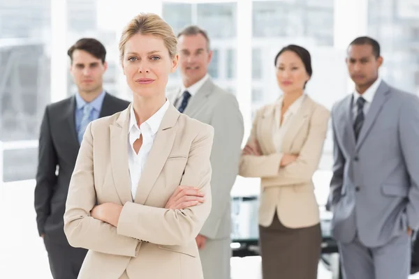 Businesswoman looking at camera with team behind her — Stock Photo, Image
