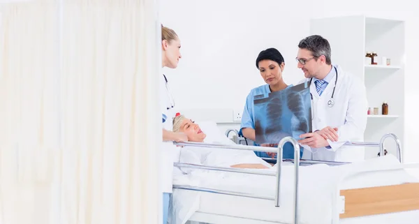 Médicos mostrando radiografía a paciente femenino en cama —  Fotos de Stock