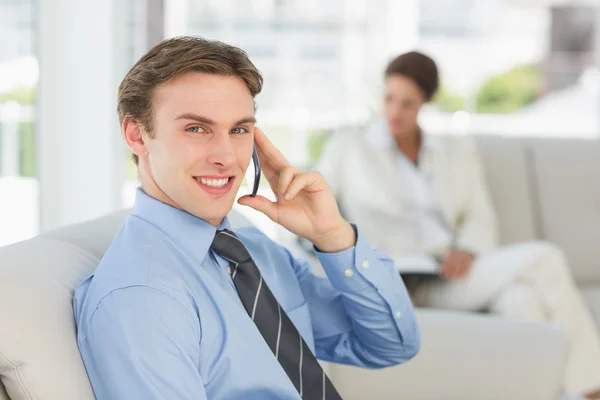 Smiling businessman on the phone sitting on couch — Stock Photo, Image