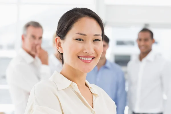 Feliz asiático mujer de negocios de pie con equipo detrás de su —  Fotos de Stock