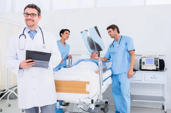 Doctors holding reports by patient at hospital — Stock Photo, Image