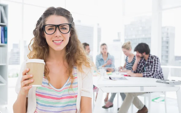 Mujer sosteniendo taza de café desechable con colegas en backgroun —  Fotos de Stock