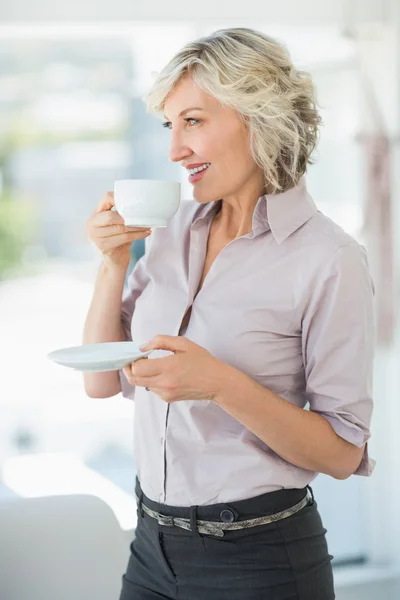 Lächelnde schöne Geschäftsfrau, die im Büro Tee trinkt — Stockfoto