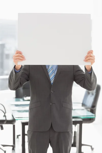 Empresário segurando cartaz sobre seu rosto — Fotografia de Stock