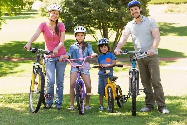 Familj på fyra med cyklar i parken — Stockfoto