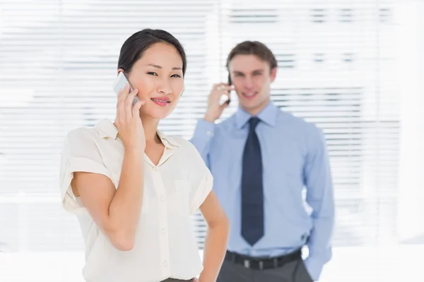 Geschäftsfrau und Mann benutzen Mobiltelefone im Büro — Stockfoto