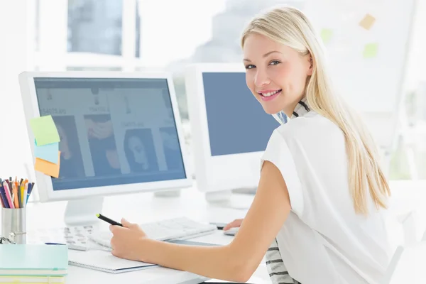 Casual young woman using computer in office — Stock Photo, Image