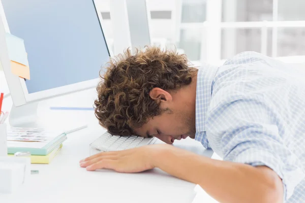 Casual affärsman med huvudet över tangentbordet på skrivbord — Stockfoto