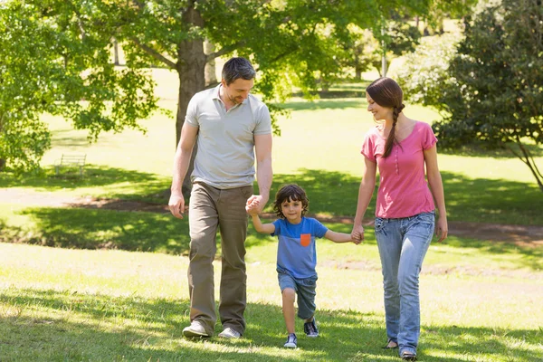 Family of three holding hands and walking at park — Stock Photo, Image